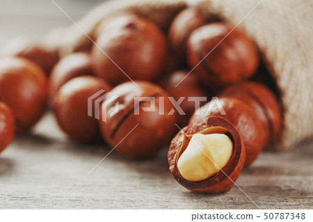 Macadamia nut on a wooden table in a bag, closeup, 50787348