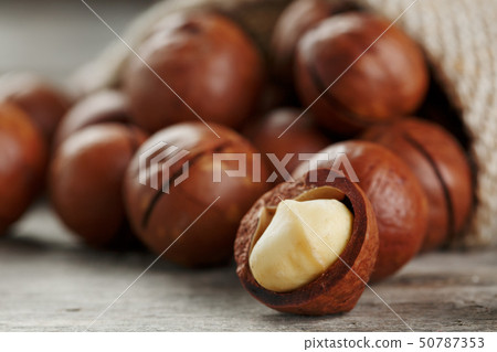 Macadamia nut on a wooden table in a bag, closeup, 50787353