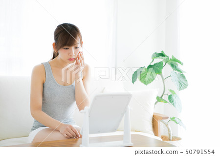 Woman checking skin with mirror Woman checking skin with mirror 50791554