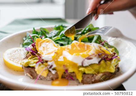 Young woman eat breakfast with knife and fork, Morning in cafe. Healthy breakfast with wholemeal 50793812