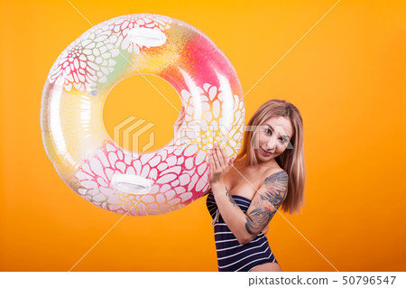 Portrait of gorgeous young woman looking at the camera and playing with colorful swimming ring in 50796547