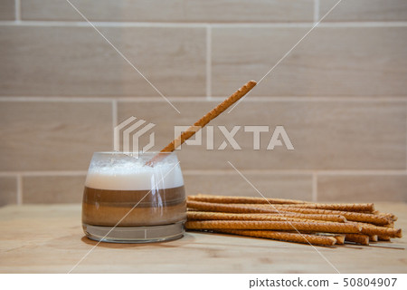 multilayer coffee or cappuccino in a glass cup with bread straw 50804907