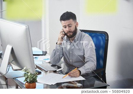 Office worker talking on mobile phone at office Office worker talking on mobile phone at office 50804920