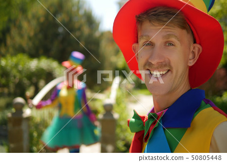 couple of funny clowns, a guy and a girl in a beautiful summer park, on a background of greenery 50805448