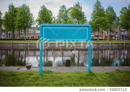 Empty blue signboard in a neighbourhood near a river, space for text Empty blue signboard in a neighbourhood near a river, space for text 50805518