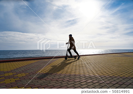 Man on scooter at sunset, silhouette, free space 50814991