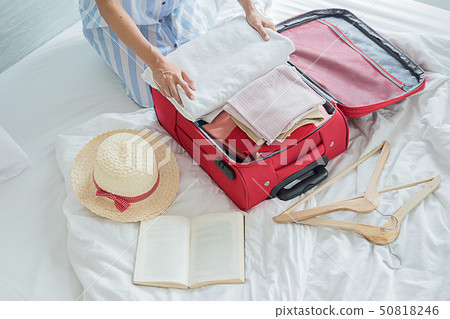 People packed suitcase with travel accessories on 50818246
