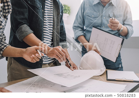 Engineers discuss a blueprint while checking Engineers discuss a blueprint while checking 50818283
