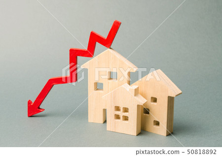 Miniature wooden houses and a red arrow down.  50818892