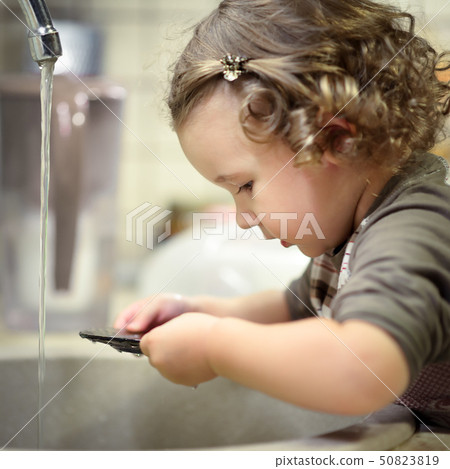 Little child is washing dishes in kitchen Little child is washing dishes in kitchen 50823819