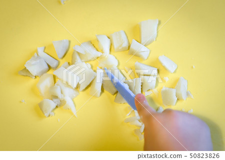 Kid cuts with a toy knife potatoes in kitchen Kid cuts with a toy knife potatoes in kitchen 50823826