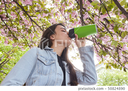 Young attractive girl drinking on the cherry tree street Young attractive girl drinking on the cherry tree street 50824890