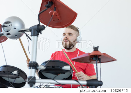 Drummer, hobbies and music concept - young man drummer in red shirt playing the electronic drums Drummer, hobbies and music concept - young man drummer in red shirt playing the electronic drums 50826745