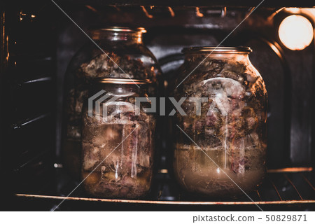 Glass jars with a stewed pork in hot oven Glass jars with a stewed pork in hot oven 50829871