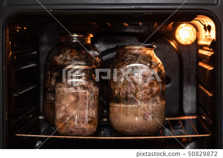 Glass jars with a stewed pork in hot oven Glass jars with a stewed pork in hot oven 50829872