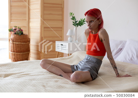 Skinny woman with bulimia sitting on her bed in the bedroom Skinny woman with bulimia sitting on her bed in the bedroom 50830084