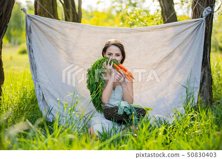 woman with vegetables sits near the trees woman with vegetables sits near the trees 50830403