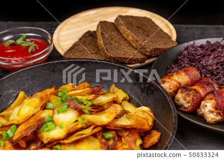 Roasted potato in the pot, pieces of rye black 50833324