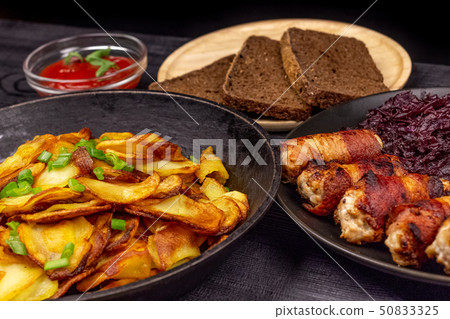 Roasted potato in the pot, pieces of rye black 50833325