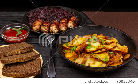 Roasted potato in the pot, pieces of rye black 50833340