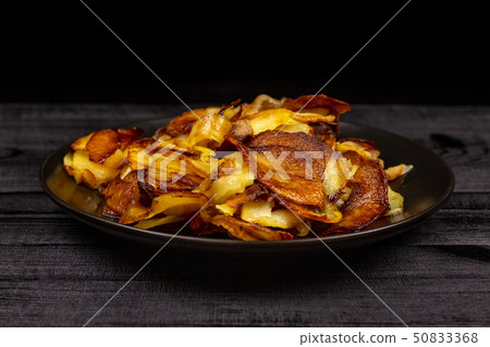 Fried homemade potato chips in a black plate on a 50833368