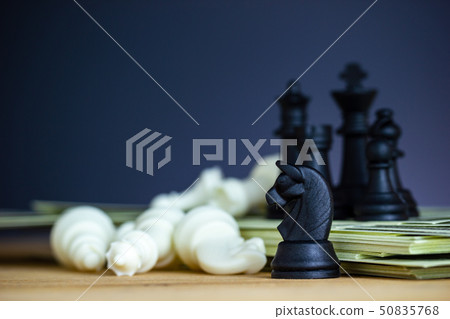 Black chess stands on top of dollar banknotes. 50835768