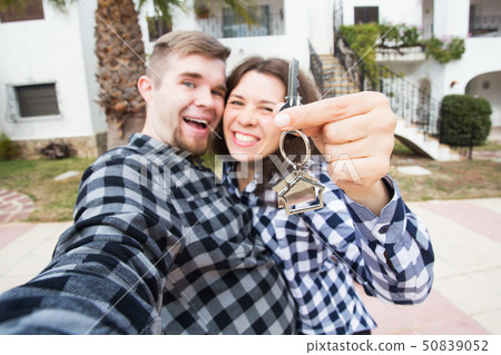 Real estate and property concept - Happy couple holding keys to new home and house miniature Real estate and property concept - Happy couple holding keys to new home and house miniature 50839052