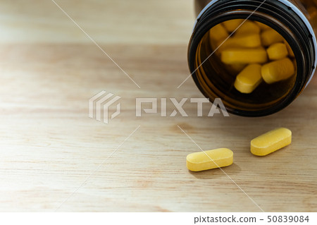 yellow tablet medicine on wood table 50839084