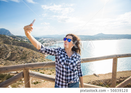 Travel, vacation and holiday concept - Happy young woman taking selfie over beautiful landscape 50839128