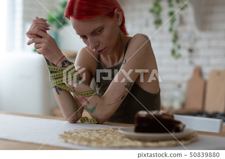 Woman with tape measure feeling dependant of eating disorder Woman with tape measure feeling dependant of eating disorder 50839880