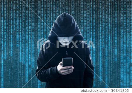 Hooded hacker with mask holding smartphone  50841805