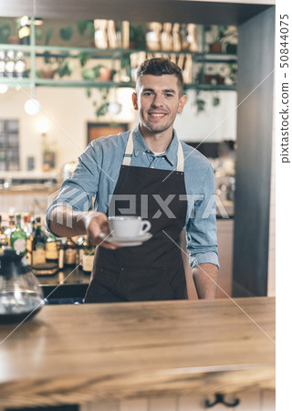 Friendly barista giving cup of coffee and smiling 50844075