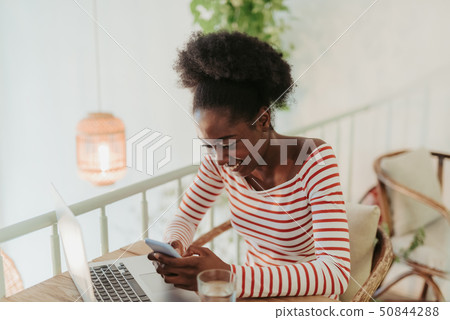 Waist up of happy African woman sitting at table in cafe Waist up of happy African woman sitting at table in cafe 50844288