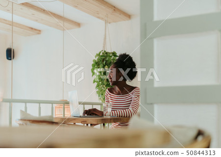 Half length of happy African woman working on laptop in cafe Half length of happy African woman working on laptop in cafe 50844313