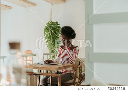 Half length of happy African woman working on laptop in cafe Half length of happy African woman working on laptop in cafe 50844316