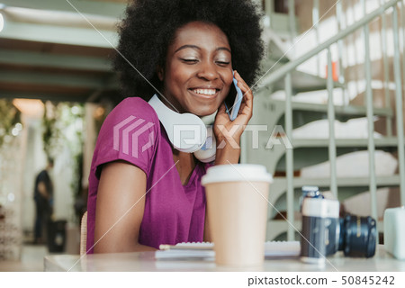 Waist up of charming African woman with headphones having chat on smartphone Waist up of charming African woman with headphones having chat on smartphone 50845242