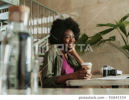 Waist up of happy young African woman having rest in cafeteria 50845334