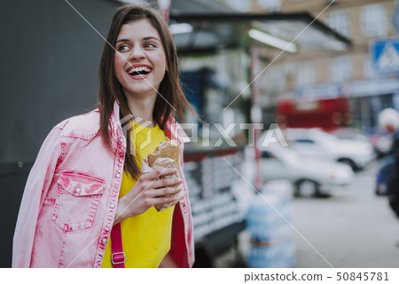Happy female walking outdoor with hot dog 50845781