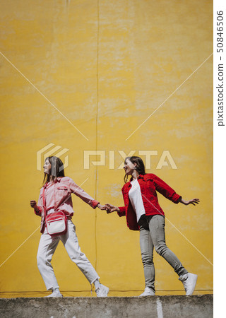 Two hipster girls walking together on parapet 50846506