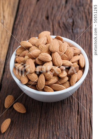 Almond nut in a ceramic bowl against wooden table Almond nut in a ceramic bowl against wooden table 50851265