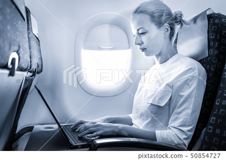 Attractive caucasian female passenger working at modern laptop computer using wireless connection on 50854727