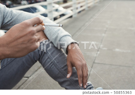 Teen Issues. Black teenager smoking cigarette, sitting alone Teen Issues. Black teenager smoking cigarette, sitting alone 50855363