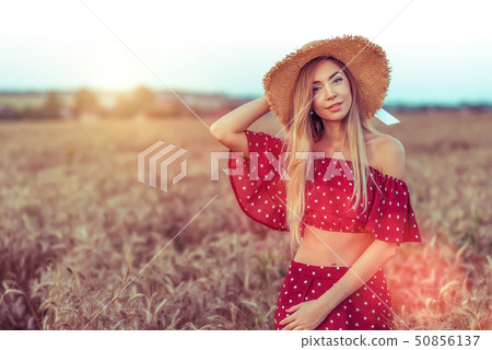 Woman in a red dress and straw hat, in wheat field in summer. Free space. The concept of healthy Woman in a red dress and straw hat, in wheat field in summer. Free space. The concept of healthy 50856137
