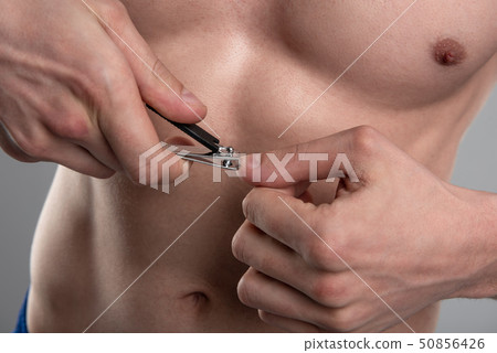 Young man cutting nails with nail clipper 50856426