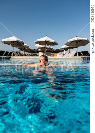 Young beautiful Woman sunbathing in swimming pool at luxurious looking on sunshade parasol in Egypt 50856845