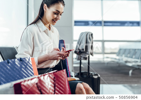 Happy woman is using smartphone in airport 50856904