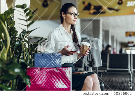 Young businesswoman is relaxing with coffee and phone in airport 50856963