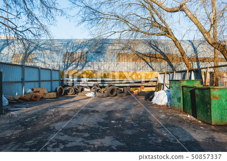 Old car tires are piled up against a fence Old car tires are piled up against a fence 50857337