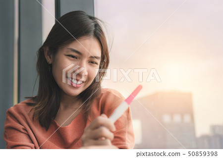 Happy young asian woman holding pregnancy test Happy young asian woman holding pregnancy test 50859398