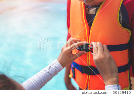 Asian mother helping her son to wear life jacket Asian mother helping her son to wear life jacket 50859410